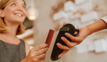 Smiling woman paying contactless in cafe